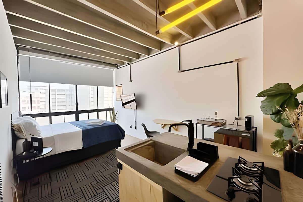 A modern bedroom with a bed, a desk, a chair, and a large window.