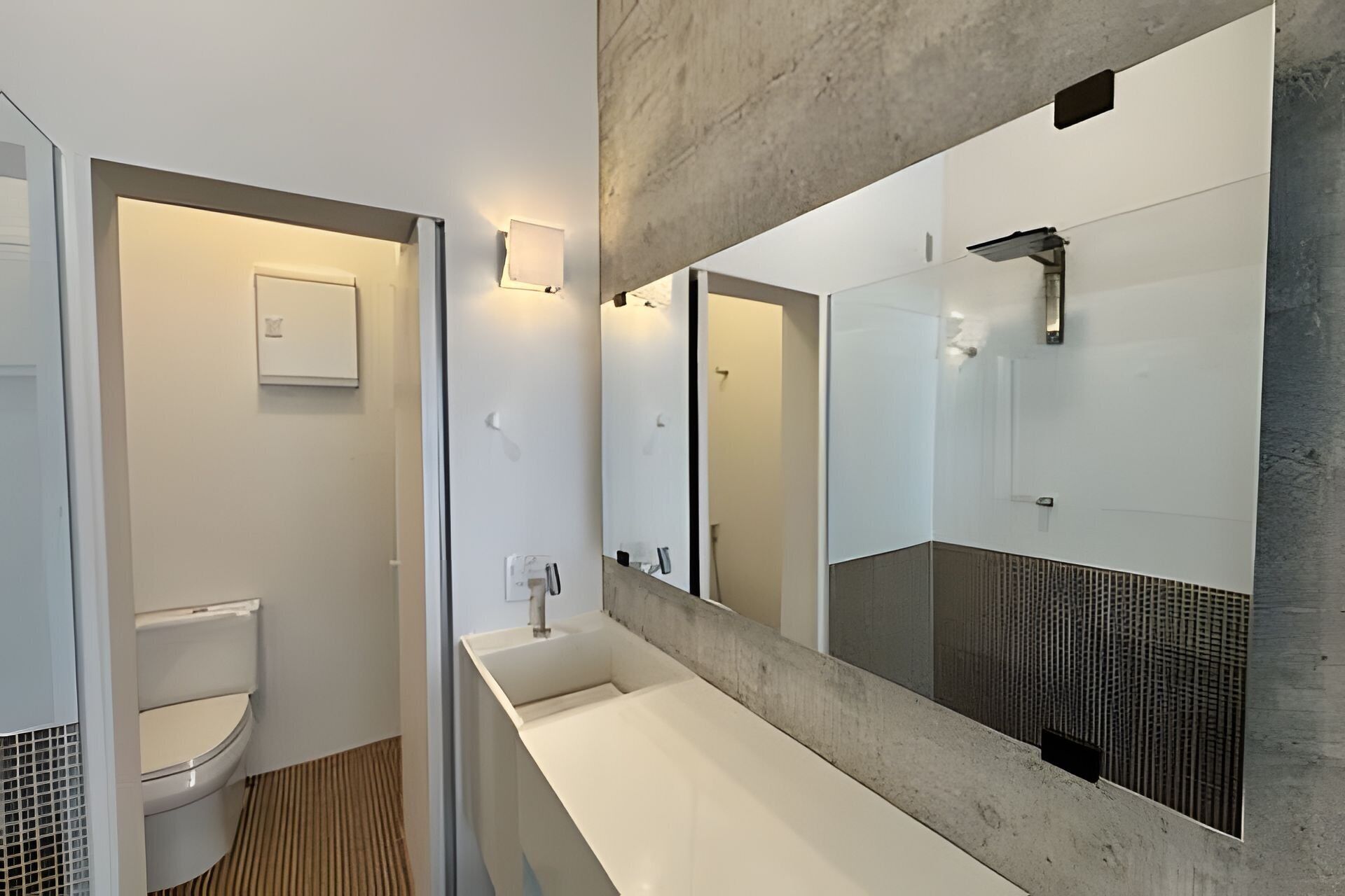 A modern bathroom with a toilet, a sink, and a large mirror.