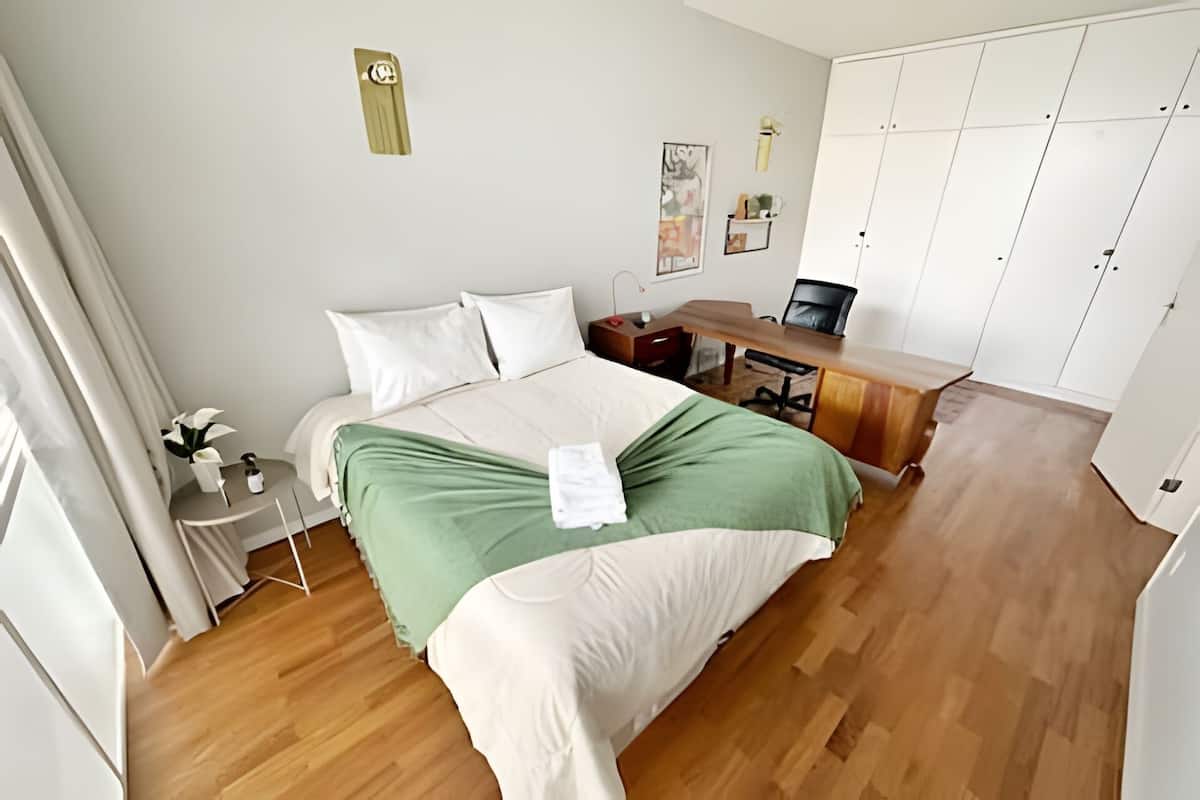A bedroom with a bed, a desk, and a wardrobe.