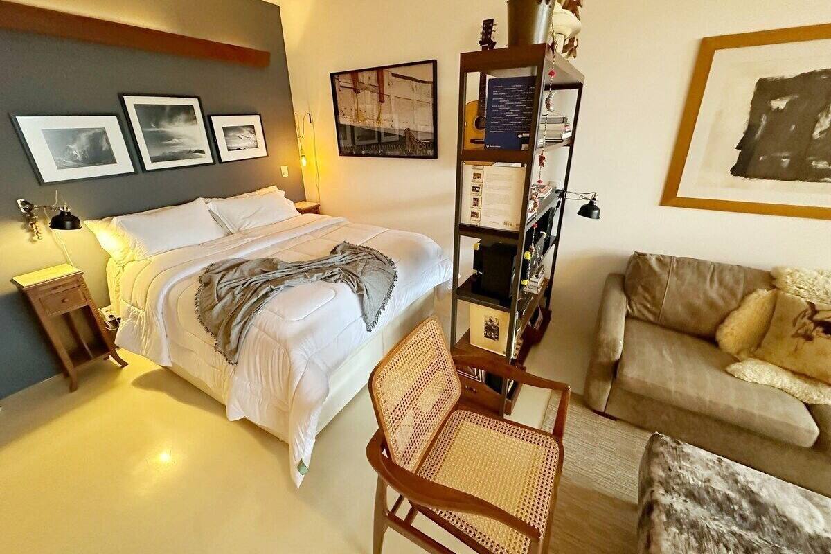 A hotel room with a bed, a wooden chair, a sofa, and a bookshelf.