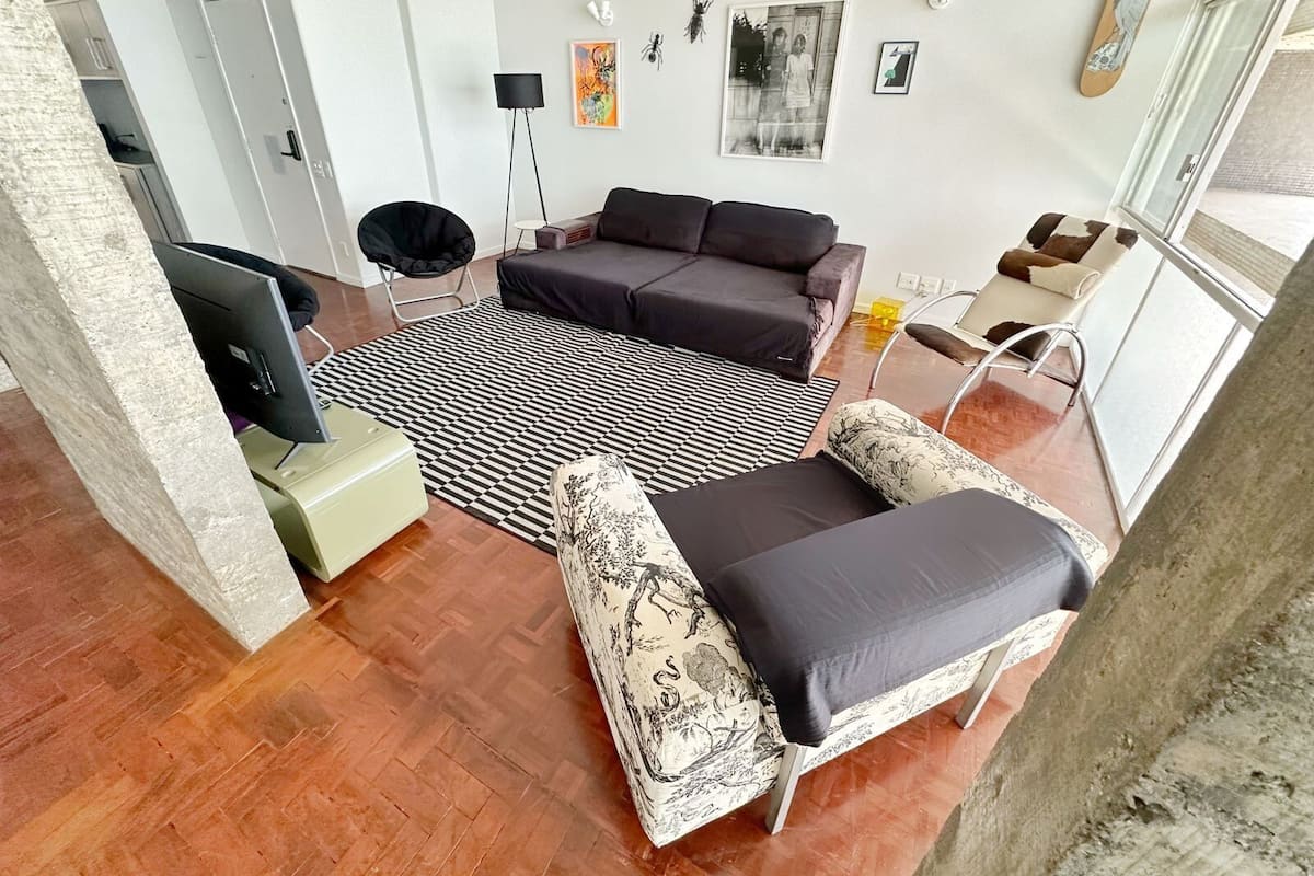 A modern living room with a sofa, armchairs, a TV, and a patterned rug.