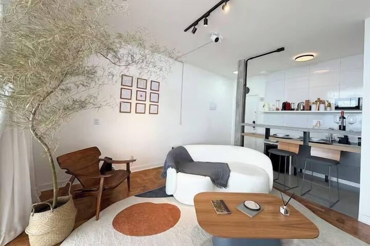 A modern living room with a white sofa, a wooden coffee table, and a large potted plant.