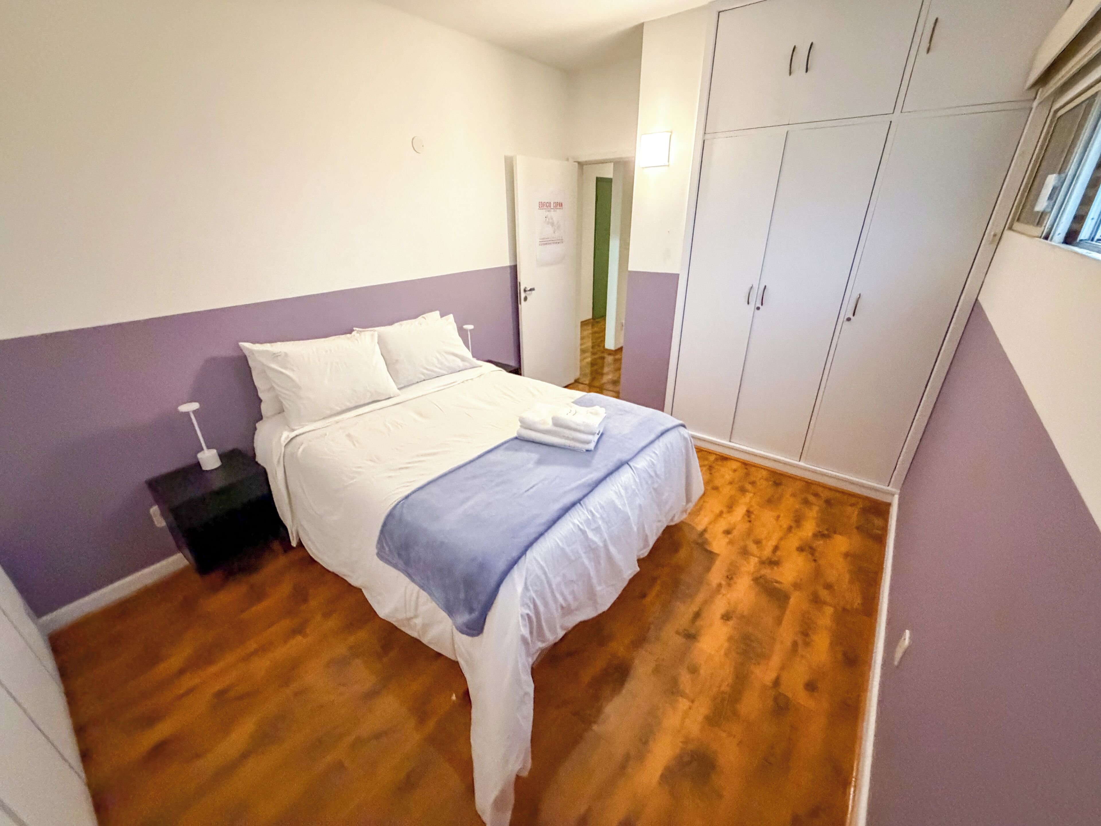 A bedroom with a bed, a wardrobe, and a nightstand.