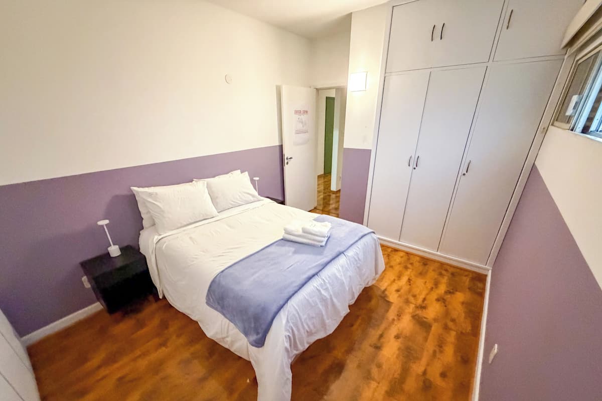 A bedroom with a bed, a wardrobe, and a nightstand.