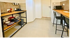 Een kleine keuken met een houten aanrecht, een zwarte hanglamp en een witte deur.