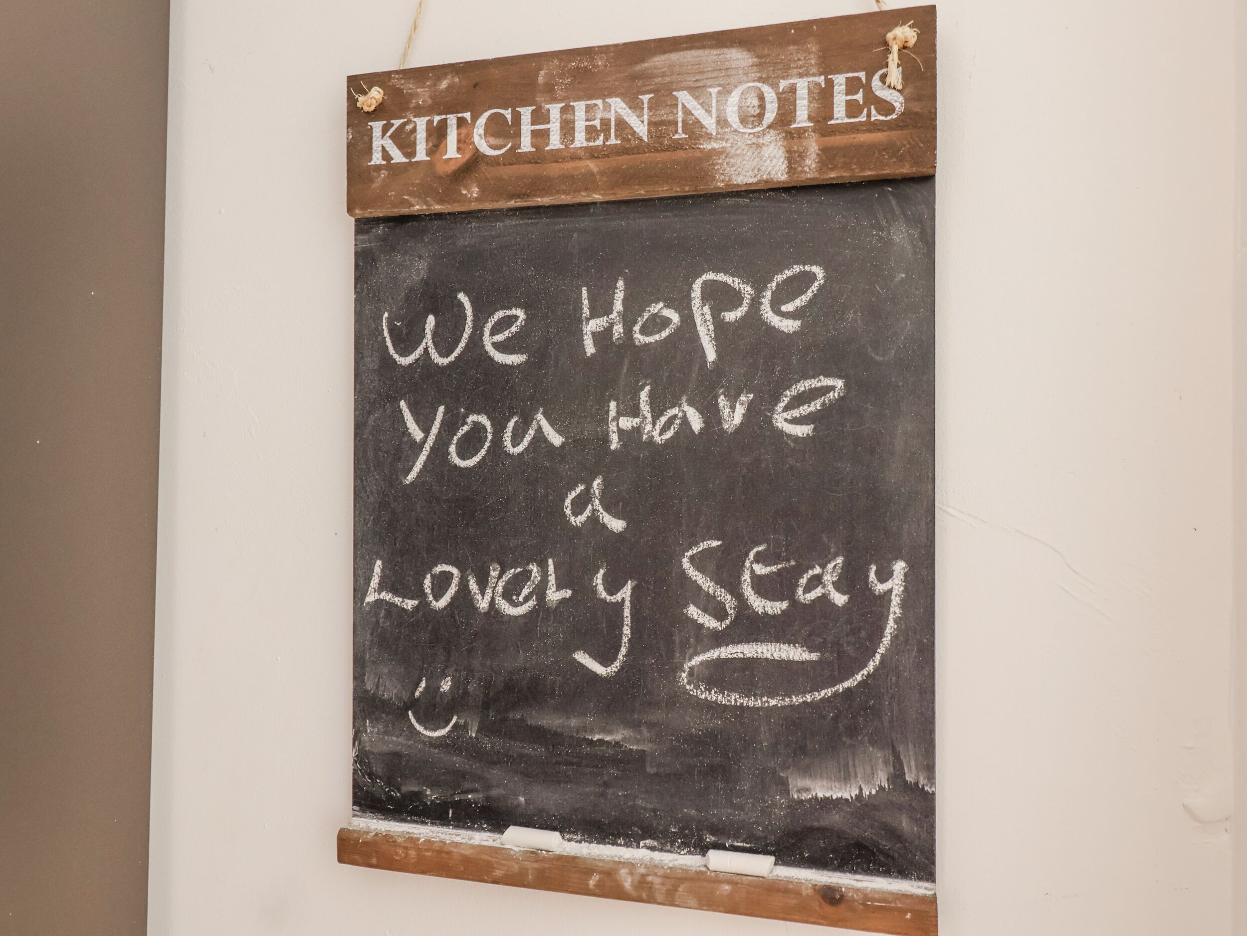 A blackboard with the text "KITCHEN NOTES" at the top and "We hope you have a lovely stay" written below.