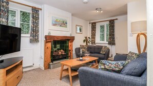 Una sala acogedora con chimenea, un sofá, una mesa de centro y un televisor.