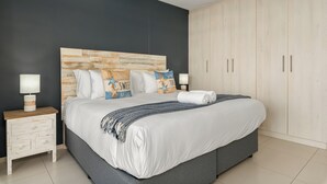Ein modernes Schlafzimmer mit einem großen Bett, einem Holz-Kopfteil und einem Kleiderschrank.