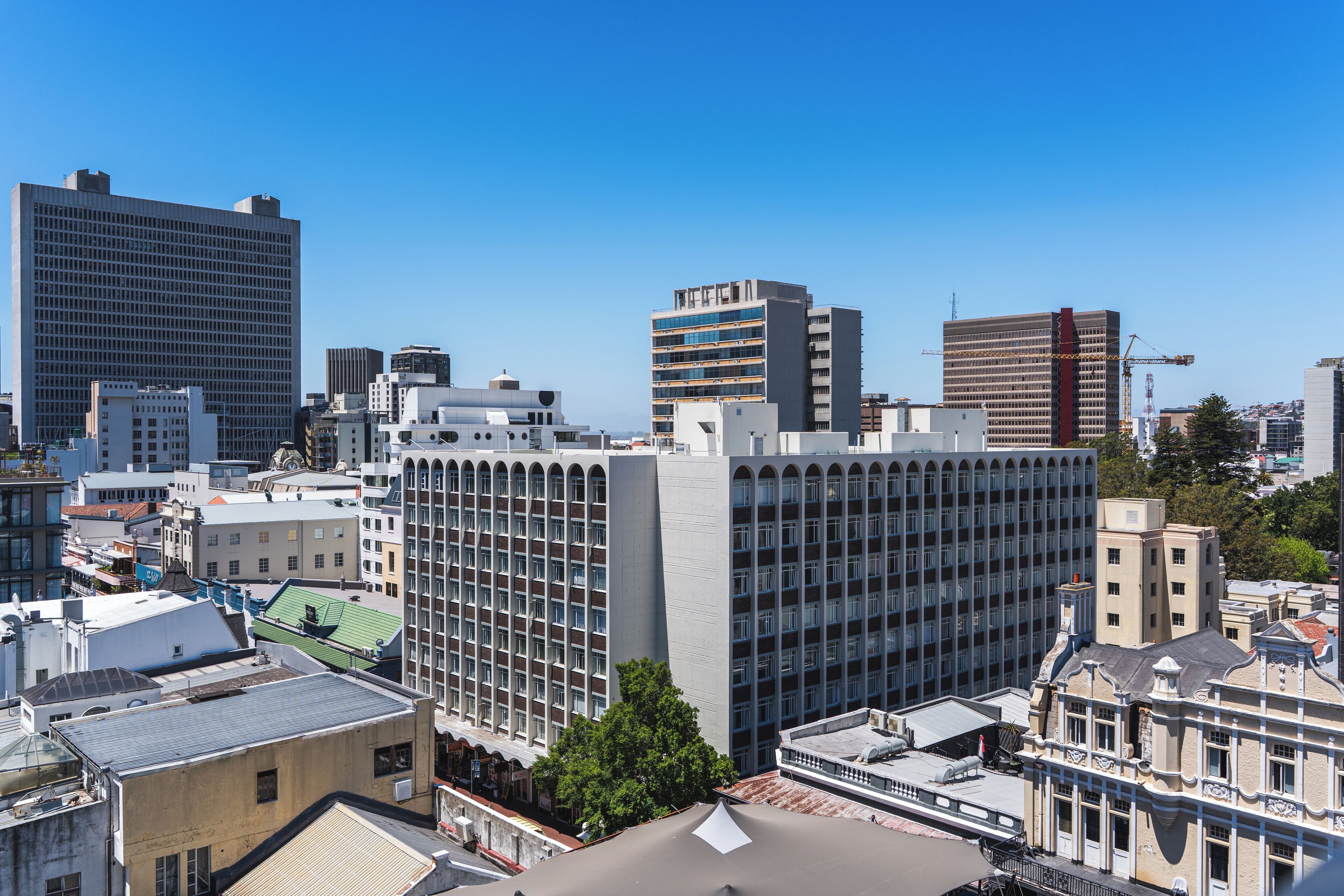 A cityscape with a variety of buildings, including a large, modern high-rise and several smaller structures.