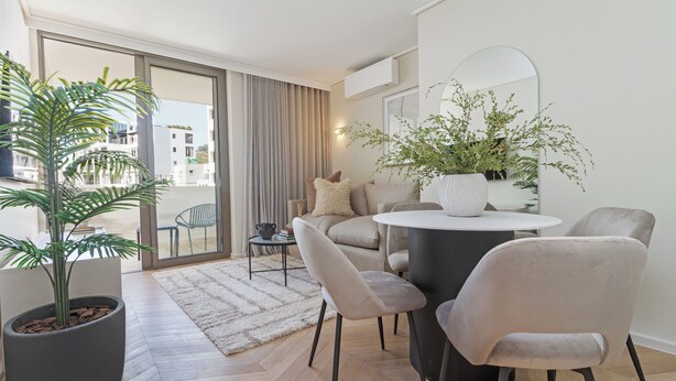 Un salon moderne avec une grande plante en pot, une table basse ronde et un canapé.
