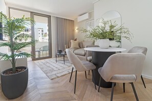 Een moderne woonkamer met een grote potplant, een ronde salontafel en een bank.