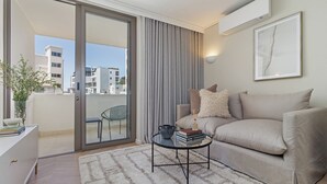 Un salon moderne avec un canapé, une table basse et une porte-fenêtre coulissante donnant sur un balcon.