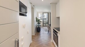 Une cuisine moderne avec des meubles blancs, un four à micro-ondes et une plante en pot.