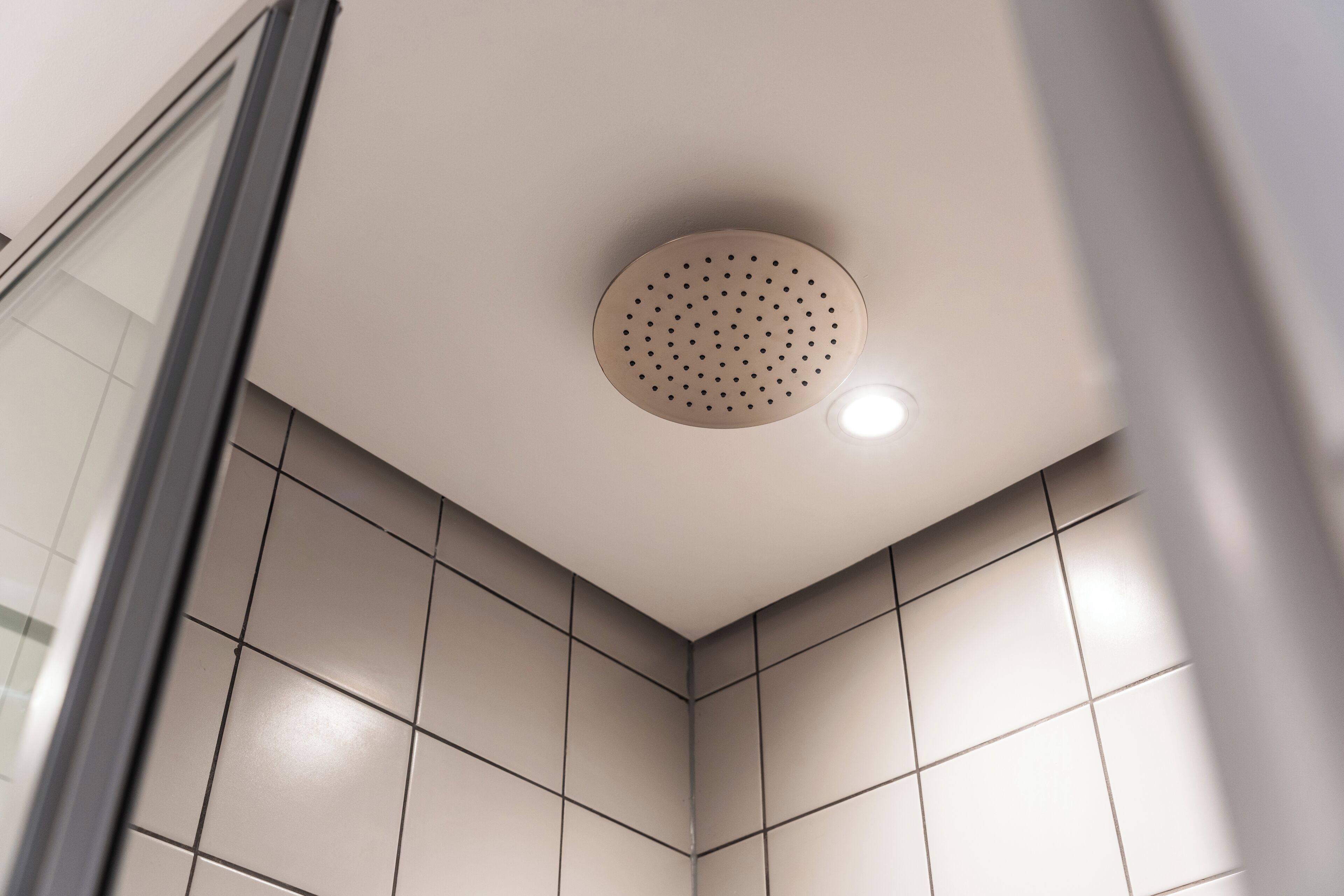 A corner of a room with a ceiling light fixture and tiled walls.