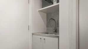 Una cucina compatta con lavello incassato, forno a microonde e piano di lavoro in granito.