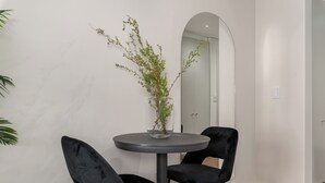 Una camera moderna con un tavolo rotondo, due sedie nere e un vaso con piante verdi.