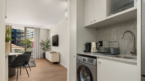 Cocina compacta con lavadora, microondas y lavamanos.