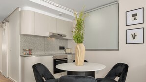 Una cocina moderna con una mesa redonda de comedor y sillas negras, una planta en maceta y cuadros en la pared.
