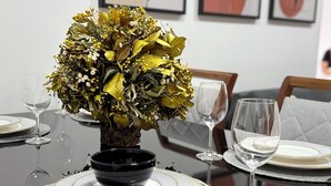 A dining table set with plates, glasses, and a centerpiece of dried flowers in a vase. - Refúgio Luxo •novo, piscina, central, ar condicionado (Montes Claros)