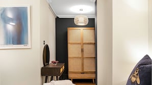 Un dormitorio con cama, mesita de noche, armario, espejo y lámpara colgante.