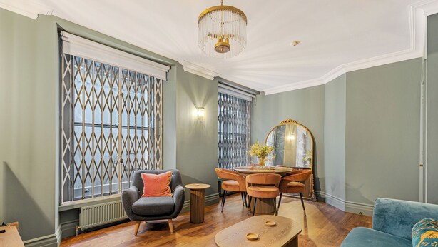 Una sala de estar moderna con comedor, que incluye una araña, un sofá, una silla y una mesa.