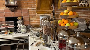 Een buffetopstelling met diverse gerechten, een klok en een fruitpresentatie.