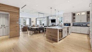 Uma cozinha moderna com ilha central, eletrodomésticos embutidos e área de refeições com uma grande janela.