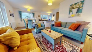 Een woonkamer met een bank, een salontafel en een eethoek met een tafel en stoelen.