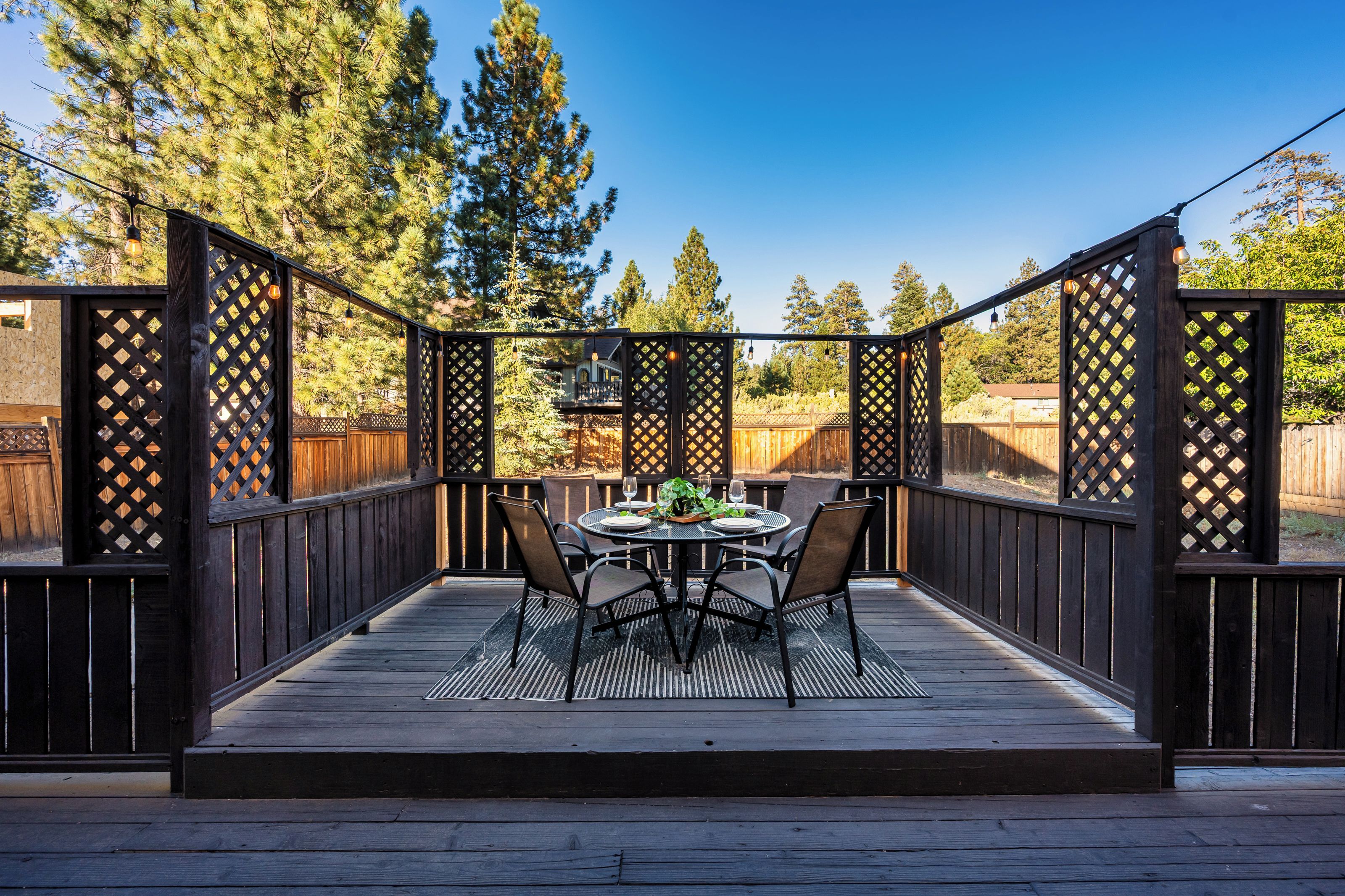 An outdoor patio with a wooden deck, a round table, and four chairs.