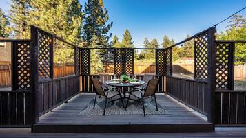 An outdoor patio with a wooden deck, a round table, and four chairs.