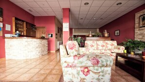Un área de recepción con mostrador de piedra, sofás florales y piso de baldosas.