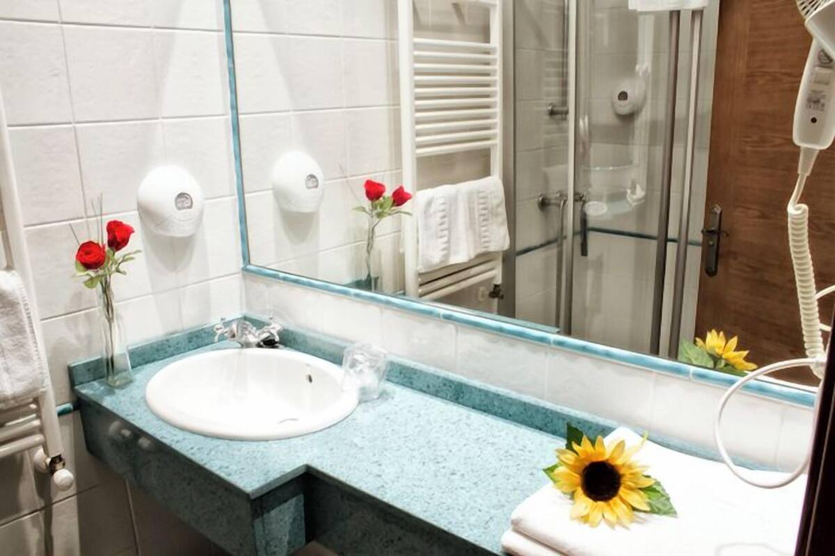 A bathroom with a white sink, a glass shower enclosure, and a hairdryer on the counter.
