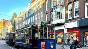 A tram on a city street with buildings and a cyclist. - Rembrandt - luxury authentic room at Museumplein (Amsterdam)