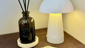 A small table with a dark glass bottle, a white lamp, and a white decorative item. - Rembrandt - luxury authentic room at Museumplein (Amsterdam)