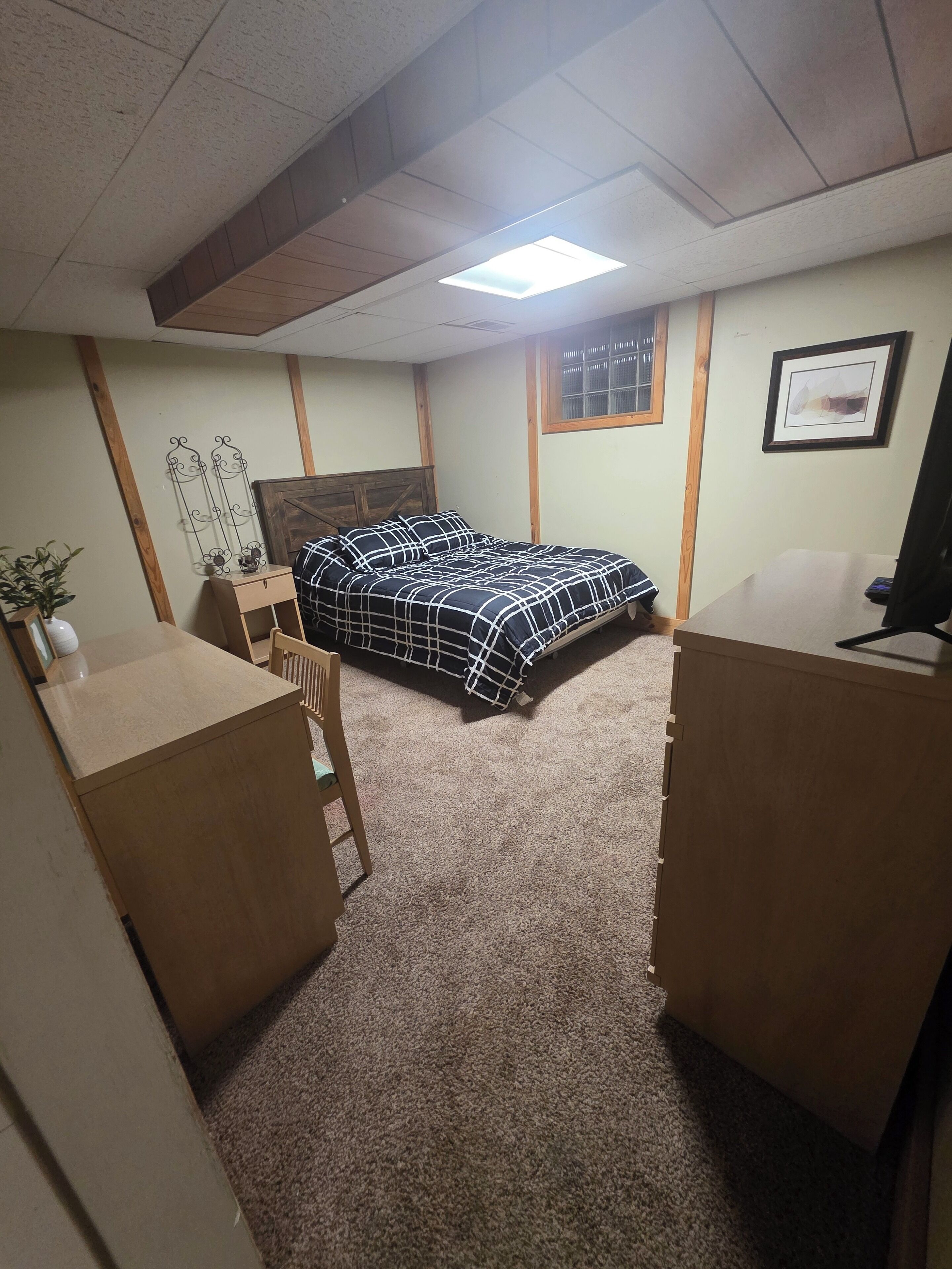 A bedroom with a bed, a desk, a chair, and a small table.