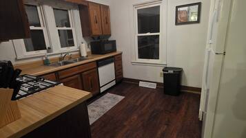 A kitchen with wooden cabinets, a microwave, a stove, a sink, and a refrigerator.