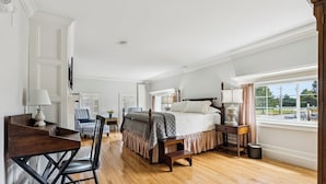 A bedroom with a bed, bedside table, lamp, chair, and a desk with a lamp. - Mayville Union House (Bethel)