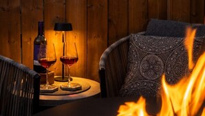 A cozy outdoor seating area with a fire pit, a table with two glasses of red wine, and a bottle of wine. - king/Hot Tub/full kitchen/private Backyard/BBQ/W/D (Lethbridge)