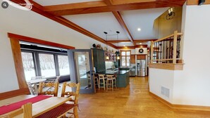 Una cocina amplia con armarios de madera, un comedor con mesa y sillas, y una escalera que sube a otro nivel.