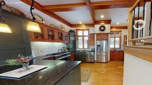 Una cocina amplia con armarios de madera, un refrigerador de acero inoxidable y una escalera de madera.