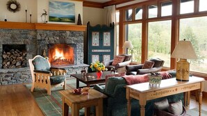 Una sala de estar acogedora con chimenea de piedra, asientos cómodos y ventanas amplias que ofrecen vistas al exterior.