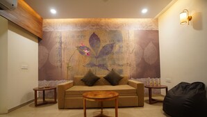 A living room with a sofa, a coffee table, a bean bag, and a decorative wall with script. - RAAHI HOMESTAY (Ujjain)