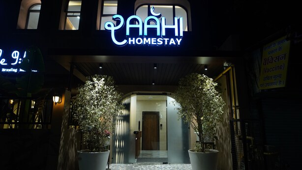 A hotel entrance with a neon sign reading "AAHI HOMESTAY" and a signboard in a foreign language. - RAAHI HOMESTAY (Ujjain)