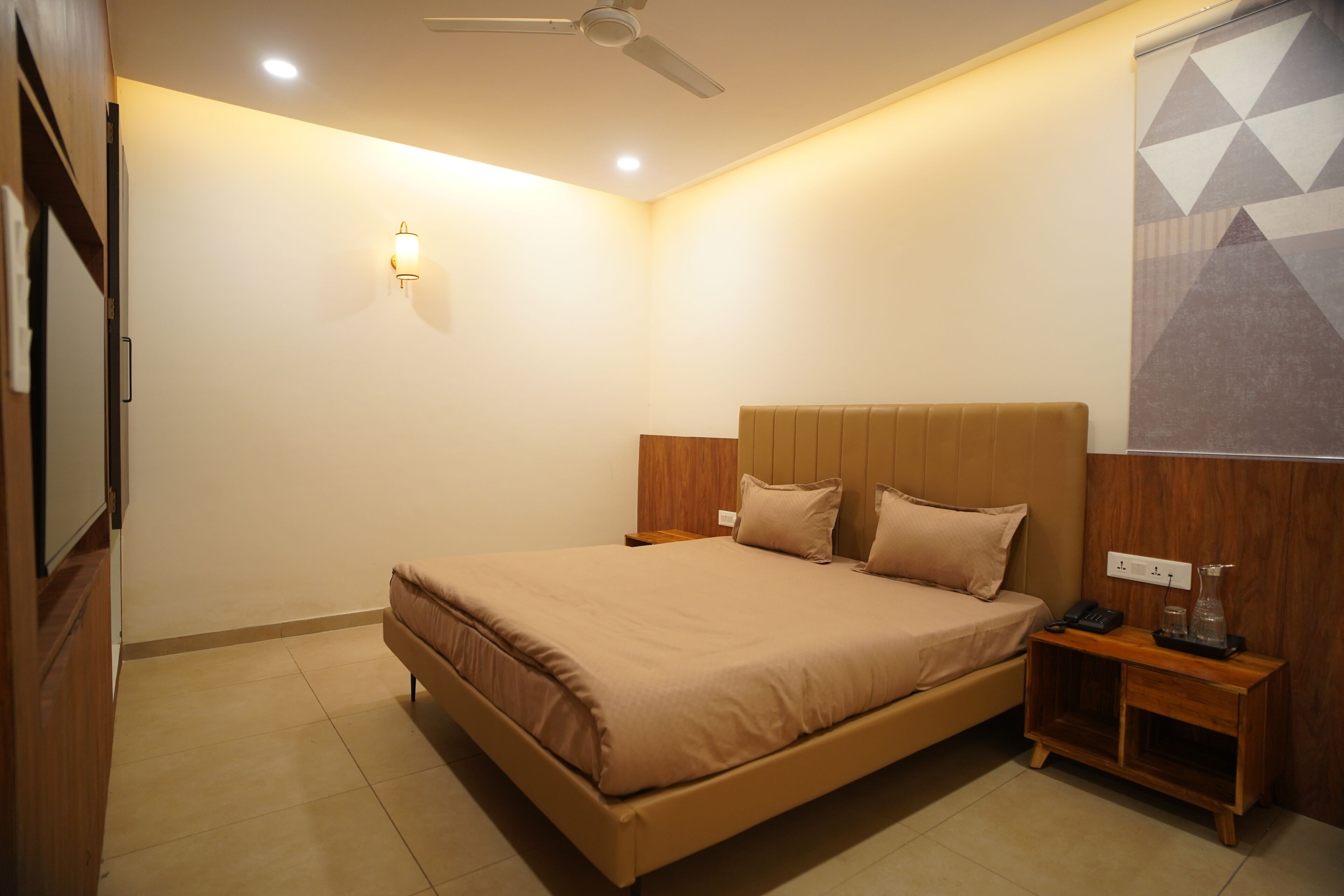 A bedroom with a bed, nightstands, a ceiling fan, and a wall-mounted light fixture.