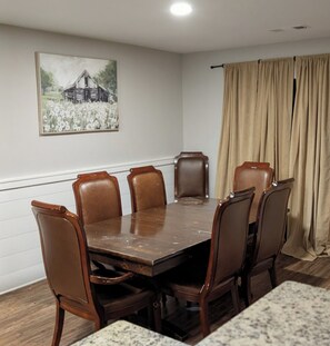 A conference room with a wooden table and leather chairs, a painting on the wall, and beige curtains. - Secluded Water Front (Sanger)