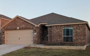 A two-story brick house with a garage, a large window, and a well-maintained lawn. - Secluded Water Front (Sanger)