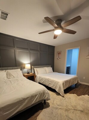 A hotel room with two beds, a ceiling fan, a nightstand with a lamp, and a door leading to another room. - Secluded Water Front (Sanger)