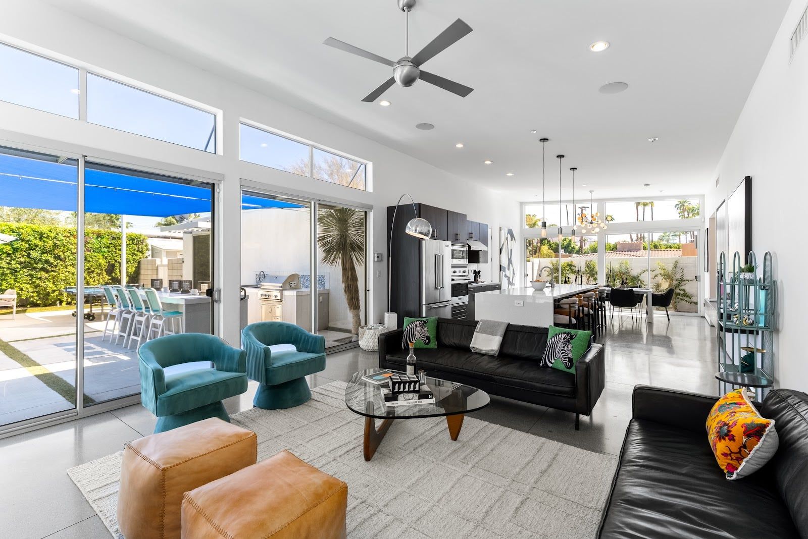 A modern living room with a sofa, chairs, a coffee table, and a dining area with a table and chairs.