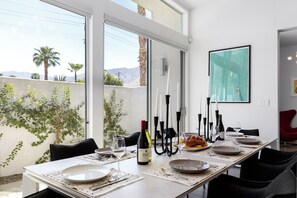 A dining area with a table set for four, a bottle of wine, and candles. - Modern Desert Oasis – Luxury Retreat (Palm Springs)