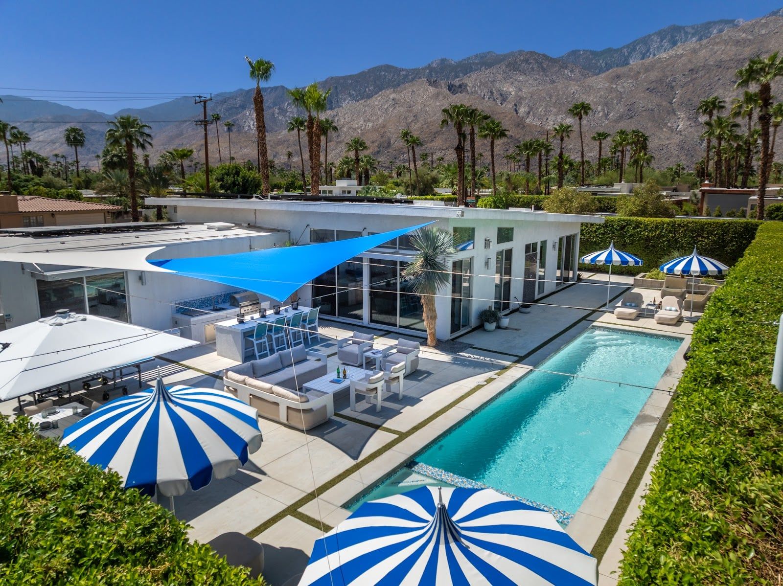 A rooftop pool area with lounge chairs, umbrellas, and a view of mountains.